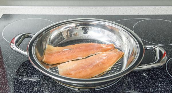 Introducir los filetes de pescado en la paellera con el lado de la piel hacia abajo y colocar la tapa.