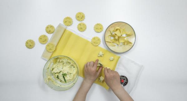 Extender la masa para pasta y, si es necesario, marcar la forma de los raviolis de unos 5 cm Ø en la mitad de la masa. Colocar pequeños trozos de relleno encima y mojar la pasta con un poco de agua con la ayuda de un cepillo.