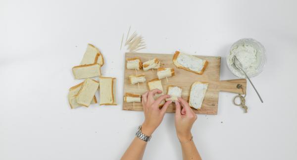 Untar cada tira de pan con un poco de crema de queso, enrollar y fijar con palillos.