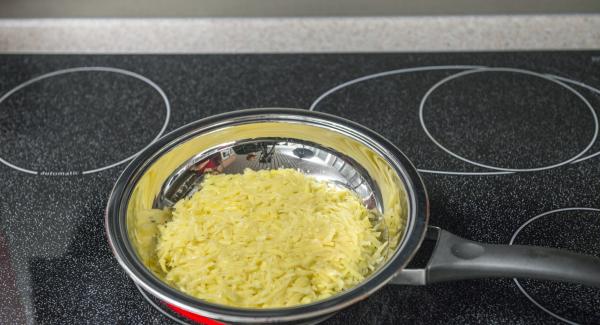 Colocar la sartén en el fuego a temperatura máxima. Añadir las patatas ralladas, extender, prensar ligeramente con una espátula y poner la tapa. Encender el Avisador (Audiotherm), colocarlo en el pomo (Visiotherm) y girar hasta que se muestre el símbolo de “chuleta”.