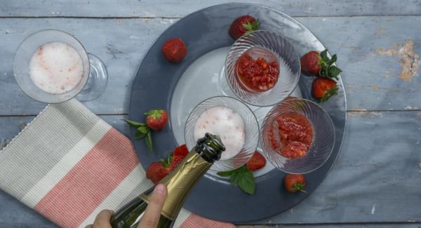 En unas copas, servir cubitos de hielo, 2-3 cucharaditas de fresas trituradas y rellenar con el prosecco/cava.