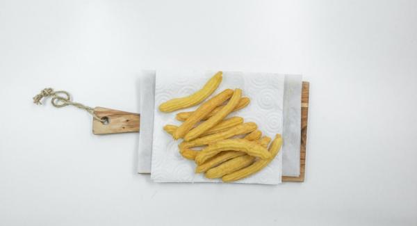 Escurrir los churros en papel de cocina y espolvorear con azúcar glas.