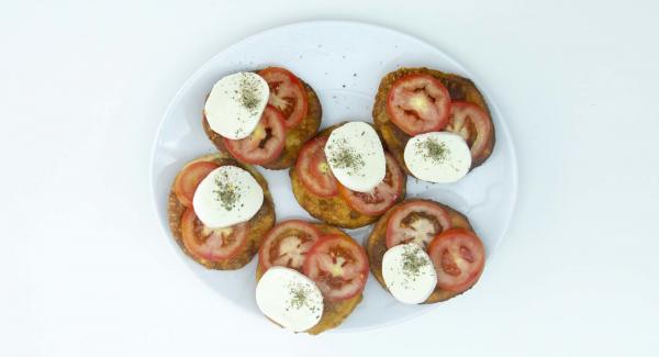 Con las pizzetas todavía calientes, añadir unas rodajas de tomate natural, unos trozos de mozzarella y orégano por encima. Servir.