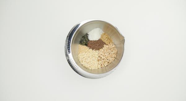 Poner las nueces en el QuickCut, cortarlas en trozos grandes y colocarlas en un recipiente con todos los ingredientes, incluidos los copos de espelta.