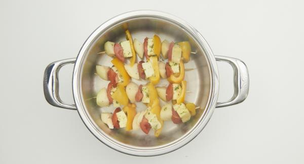 Cuando el Avisador emita un pitido al llegar a la ventana de “chuleta”, incorporar las brochetas y colocar el Navigenio en modo horno (poniéndolo invertido encima de la olla).