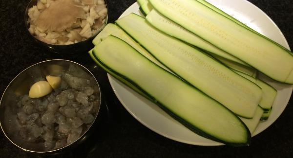 Preparamos el calabacín laminado con la ayuda de una mandolina. Cortamos las setas, los langostinos y los ajos.